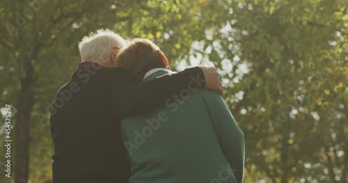 4k Back view of happy lovely caucasian senior couple sitting in bench and hugging each other . Rear view of romantic old couple sit on bench and enjoy in the open air . Happiness people . Slow Motion