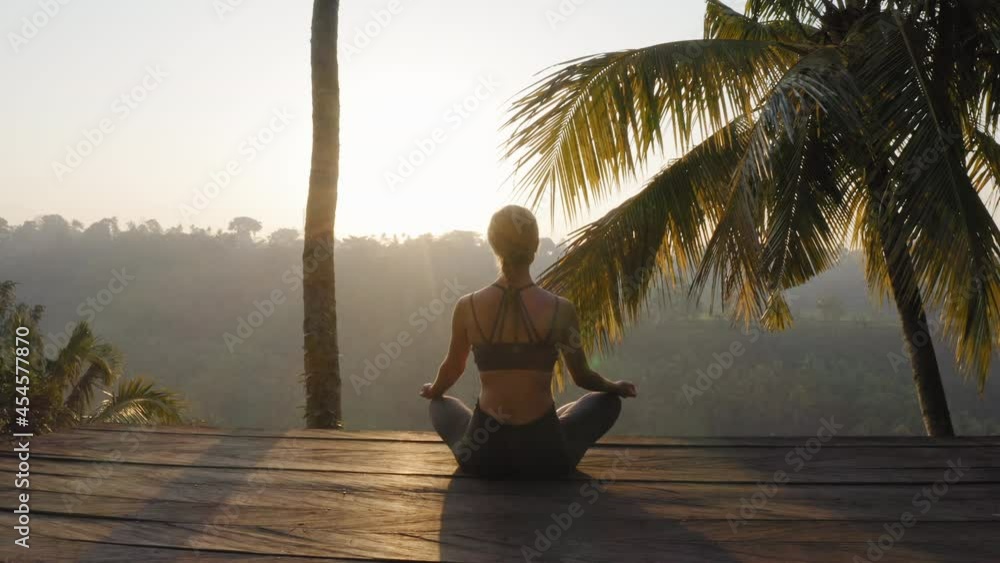 yoga woman meditating at sunrise practicing mindfulness meditation exercise sitting on deck outdoors in nature 4k