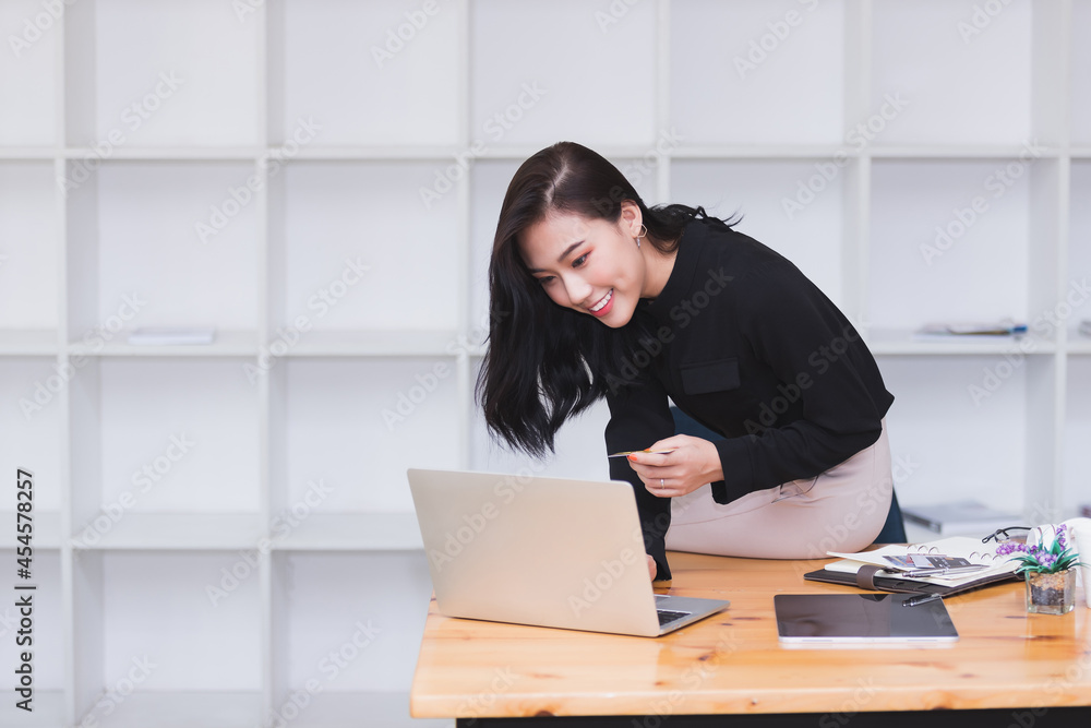 Asian businesswoman sitting on the edge of desk and working in modern office. Asian businesswoman sitting on the edge of desk and working in modern office.