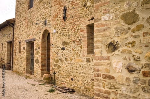 The facade of a rural stone farmhouse with wooden doors and windows in the italian countryside (Tuscany, Italy, Europe)