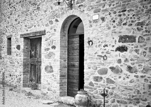 The facade of a rural stone farmhouse with wooden doors and windows in the italian countryside (Tuscany, Italy, Europe)