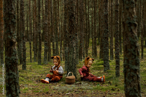 Toddler baby twins in bear bonnets sitting in the woods