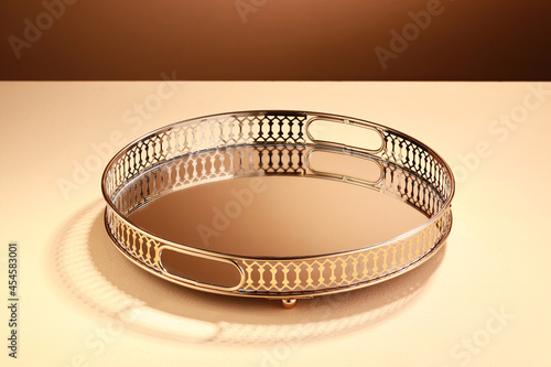 Empty Circle Gold tray on beige background with light on the wall