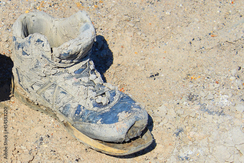 An old, dusty holey work boot with a torn off sole