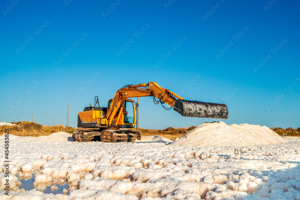 Obraz premium Sea salt harvest with yellow digger at salines in Faro, Portugal