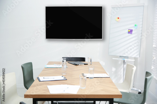 Modern wide screen TV on white wall in conference room