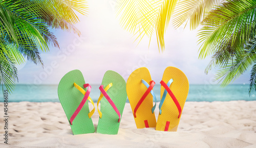 Pairs of bright flip flops on sandy beach near sea