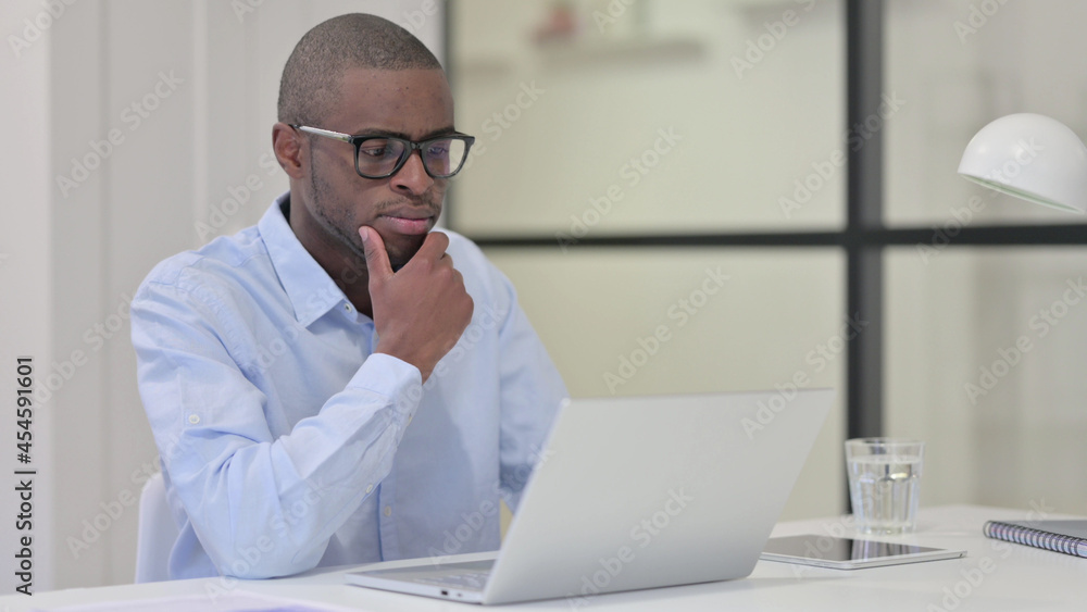 African Man with Laptop Thinking at Work African Man with Laptop Thinking at Work