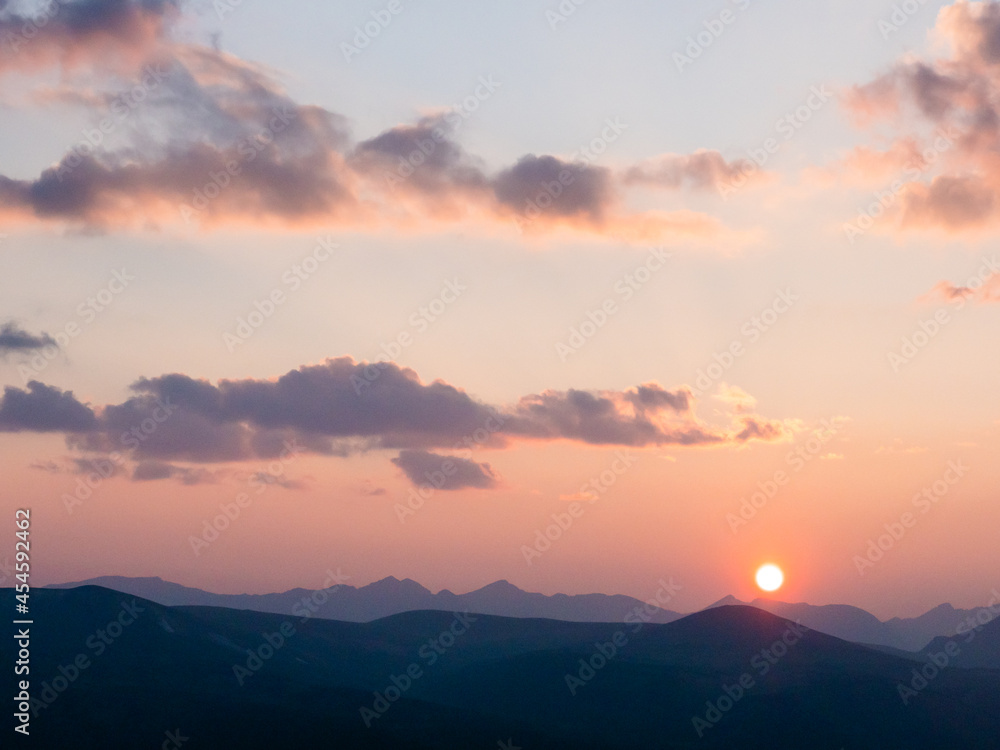 Sun setting over the peaks of the rocky mountains with pastel colored sky and pretty clouds. Sun setting over the peaks of the rocky mountains with pastel colored sky and pretty clouds.