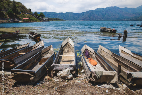 Small wooden canoes along the dirty shore with garbage of lake Atitlan, Santiago Atitlan, Guatemala photo