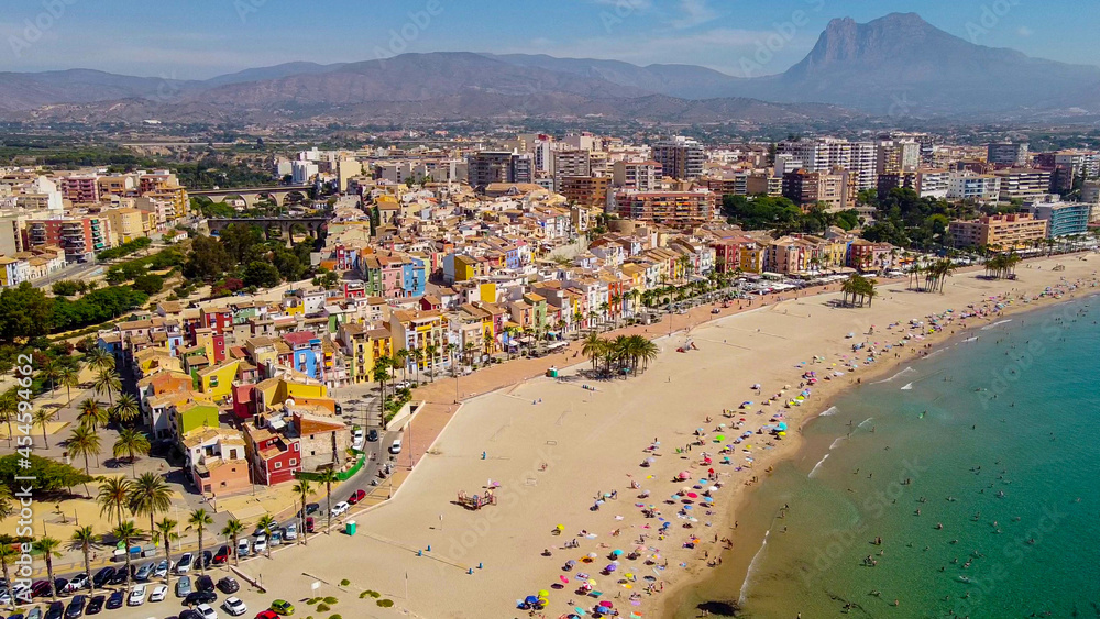 Tomas cenitales y aéreas de la ciudad y la playa de Villajoyosa en Alicante con gente tomando el sol con sus sombrillas y bañandose en el mar