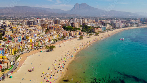 Tomas cenitales y aéreas de la ciudad y la playa de Villajoyosa en Alicante con gente tomando el sol con sus sombrillas y bañandose en el mar © Tonikko