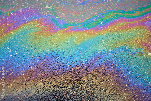 Color gasoline fuel spot on black asphalt, industrial concept. Beautiful rainbow abstract colorful background