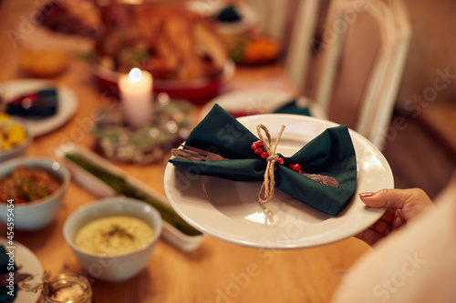 Close-up of mature woman sets the table for Christmas family dinner.