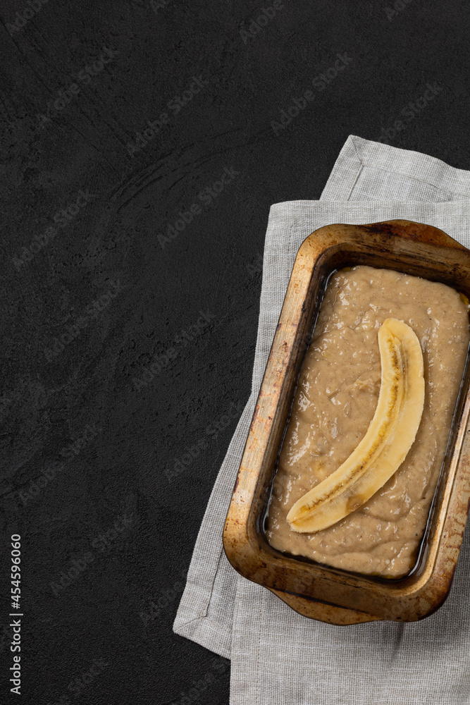 Raw banana bread dough in rectangular baking dish on black background Raw banana bread dough in rectangular baking dish on black background