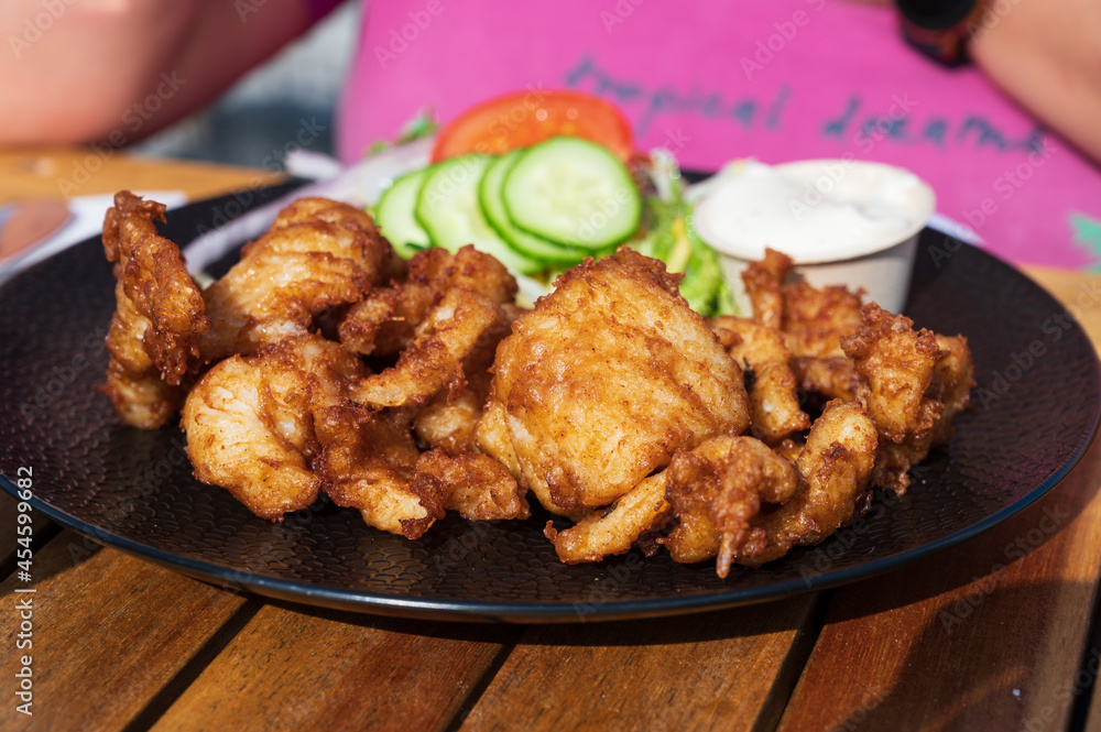 Dutch street food, fried pieces of cod fish fillet served with garlic sauce and fresh green salade Dutch street food, fried pieces of cod fish fillet served with garlic sauce and fresh green salade
