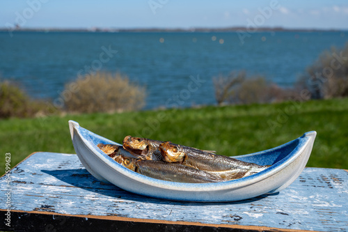 Smoked sprattus or sprats sea fish served outdoor with view on blue sea water
