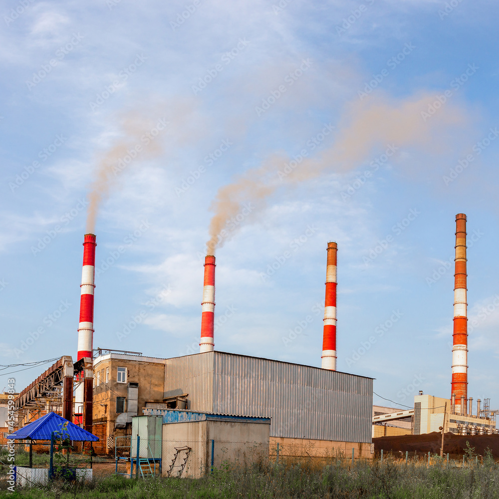 Industrial landscape with smoking chimneys of plant against blue sky background. Air environment pollution Industrial landscape with smoking chimneys of plant against blue sky background. Air environment pollution