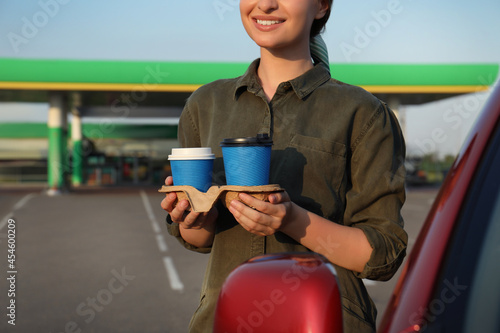 Фотография Young woman with coffee near car at gas station, closeup