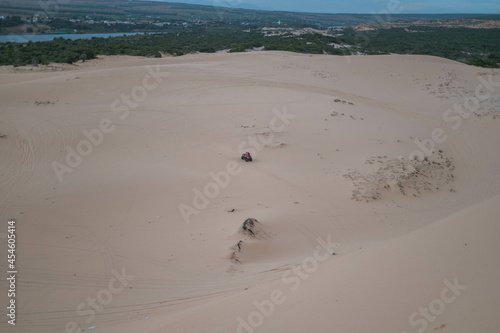 Amazing view of ATV driving in white desert and tire tracks on sand on sunny day during summer vacation. White sand dunes in tropics.