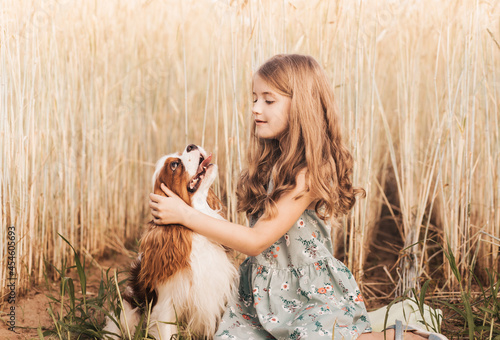 Fotografie Little girl with a cavalier king charles spaniel dog playing in the summer in na