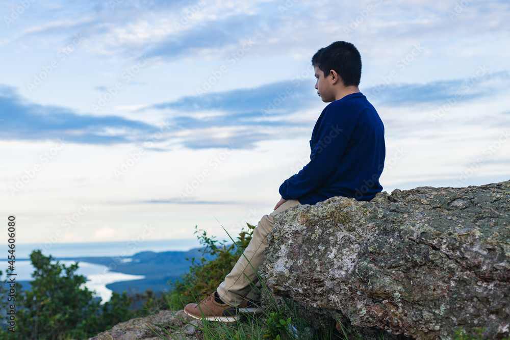 Hispanic boy sitting on the rock looking at the landscape
