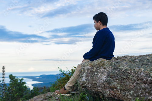 Hispanic boy sitting on the rock looking at the landscape