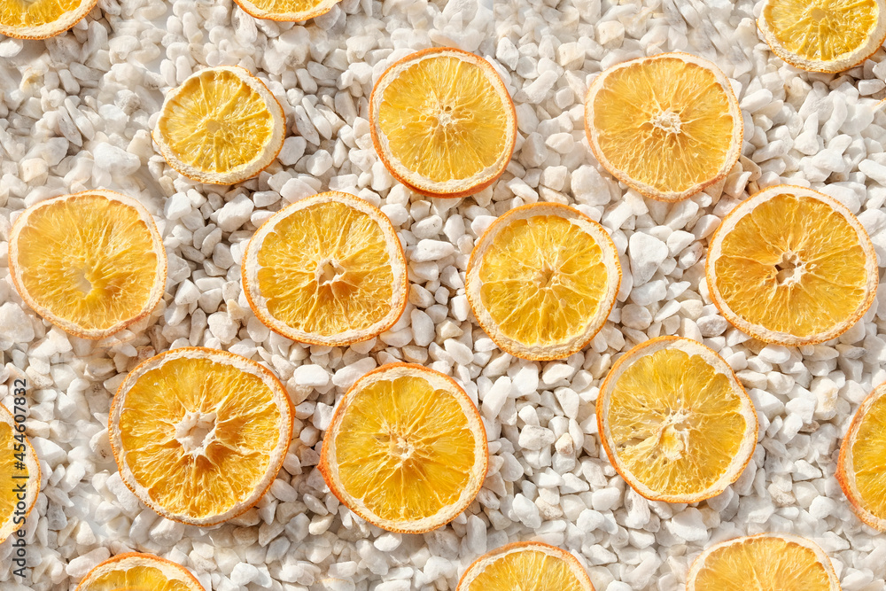 Orange chips, dehydrated fruit on a white stone background. Dried citrus product concept, storage, dessert for vegans