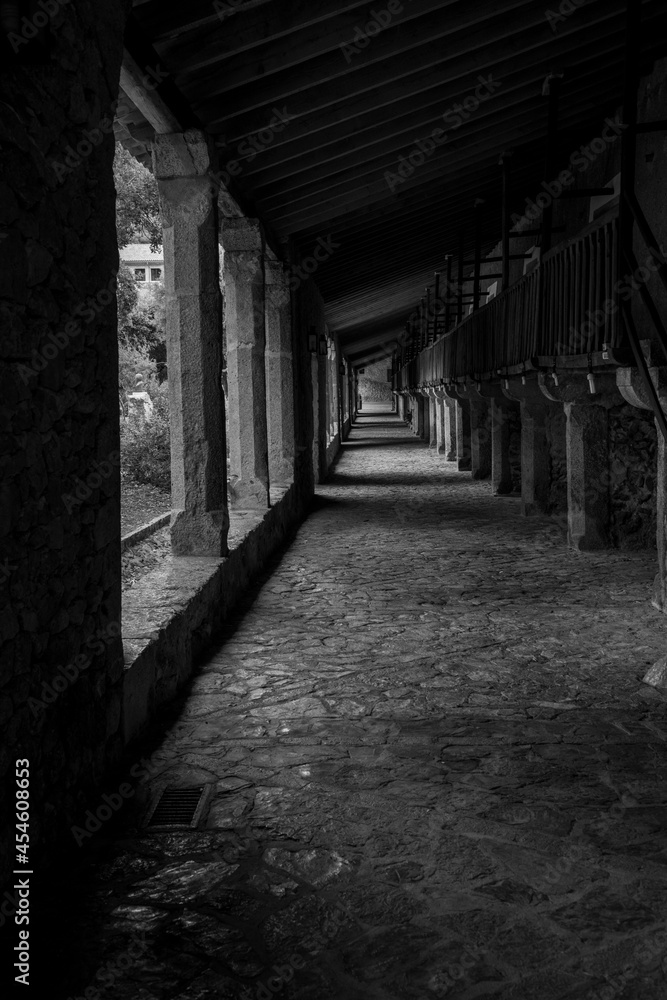along the ally, light and shadows are leading the way through the tunnel in black and white photography 
