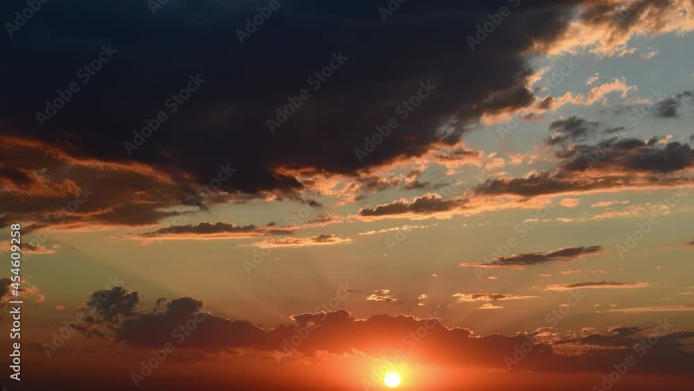 Time lapse golden sunbeams shining through gorgeous clouds moving by wind. Red orange cloudscape in sunset timelapse. Dramatic sky while sundown sun shines Time lapse golden sunbeams shining through gorgeous clouds moving by wind. Red orange cloudscape in sunset timelapse. Dramatic sky while sundown sun shines