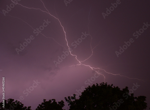 Epic spectacular lightning strike in front of cloudy night sky above forest at night