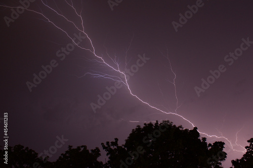 Epic spectacular lightning strike in front of cloudy night sky above forest at night