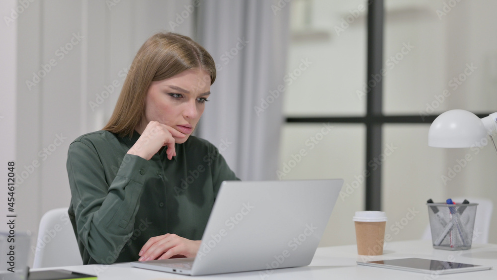 Young Woman Thinking while using Laptop at Work Young Woman Thinking while using Laptop at Work