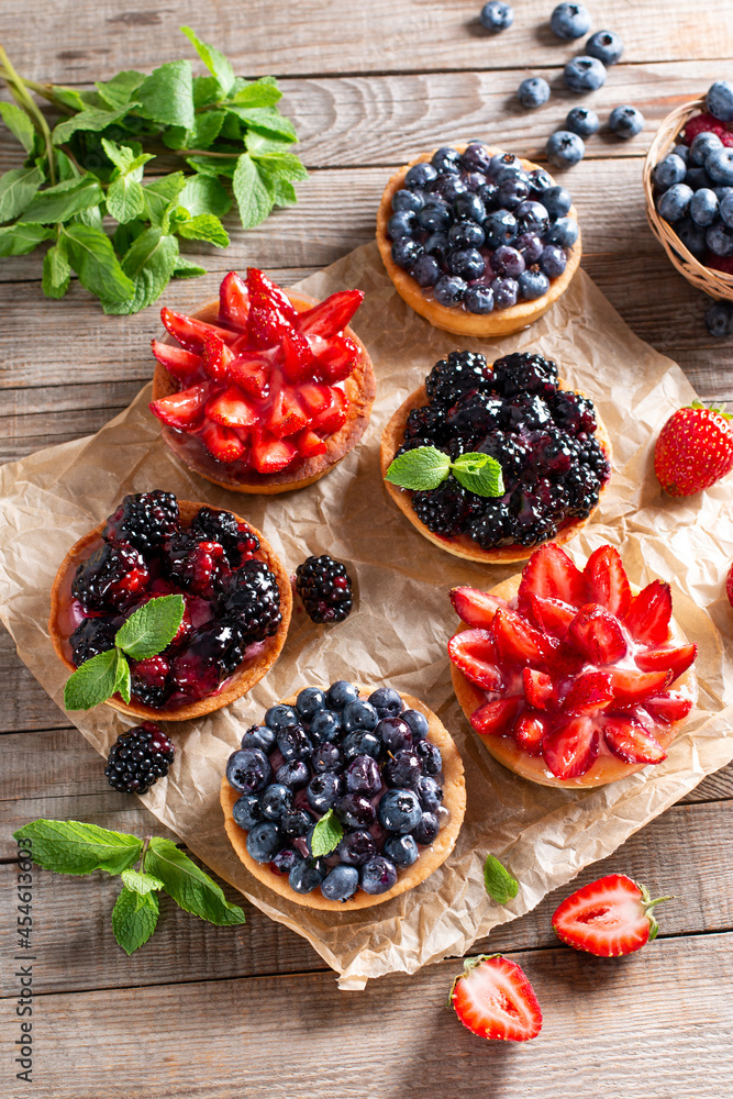 Tasty tartlets with berries on wooden table, top view.