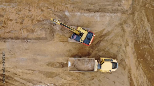 Aerial top down footage of excavator digger loading sand into sand truck photo