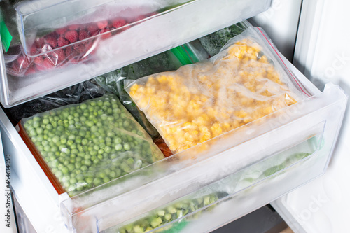 Plastic bags with different frozen vegetables in refrigerator.