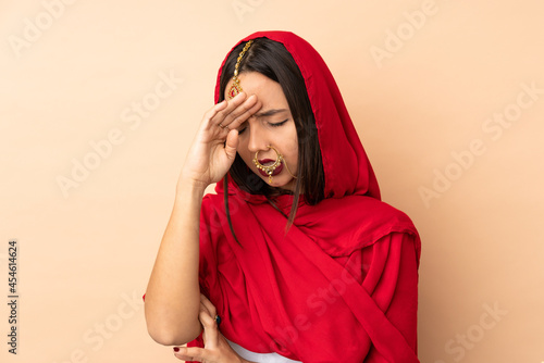 Young Indian woman isolated on beige background with tired and sick expression © luismolinero