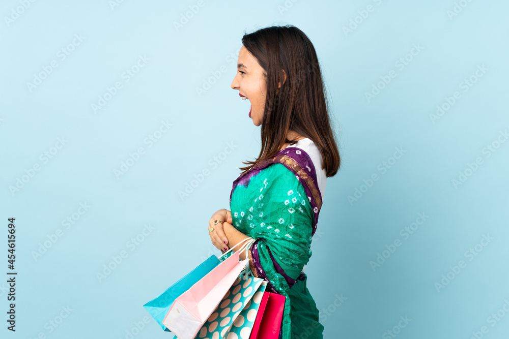 Young Indian woman with shopping bags laughing in lateral position Young Indian woman with shopping bags laughing in lateral position