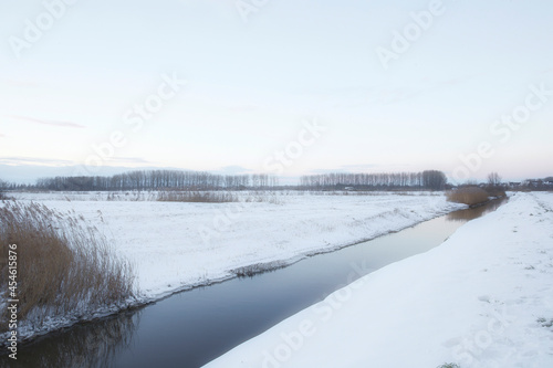 Beautiful winter landscape at sunset with fog and snow covering farmland and river in the Netherlands beautiful colors in nature