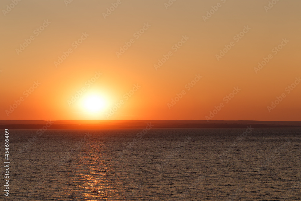 Beautiful colorful sunset over the sea. The red sun and the absence of clouds. Sea horizon. Aerial view. Landscape. The concept of a postcard picture. Light waves on the sea surface