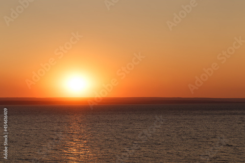 Beautiful colorful sunset over the sea. The red sun and the absence of clouds. Sea horizon. Aerial view. Landscape. The concept of a postcard picture. Light waves on the sea surface © svetlichniy_igor
