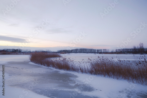 Beautiful winter landscape at sunset with fog and snow covering farmland and river in the Netherlands beautiful colors in nature