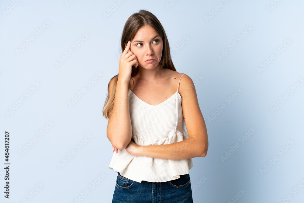 Young Lithuanian woman isolated on blue background thinking an idea Young Lithuanian woman isolated on blue background thinking an idea