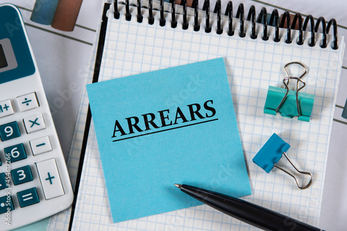 Photography ARREARS - word on a blue piece of paper against the background of a notebook, ca