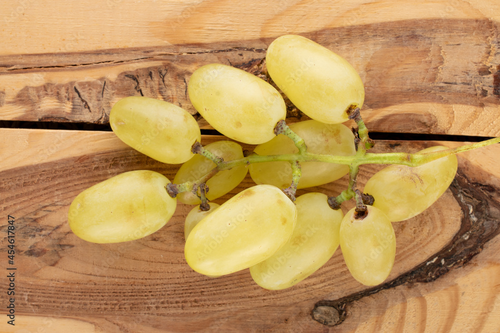 A bunch of juicy sweet grapes on a wooden table, close-up, top view.