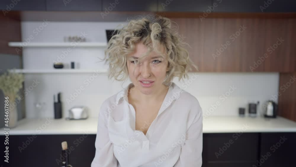 Furious beautiful young woman gesturing in slow motion and yelling looking at camera. Portrait of angry aggressive Caucasian lady posing indoors in kitchen at home Furious beautiful young woman gesturing in slow motion and yelling looking at camera. Portrait of angry aggressive Caucasian lady posing indoors in kitchen at home