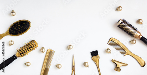 Banner with hairdressing tools in gold color and Christmas balls on a white background. A holiday template with accessories for a hair salon with space for text. Flat lay with Hairstylists scissors