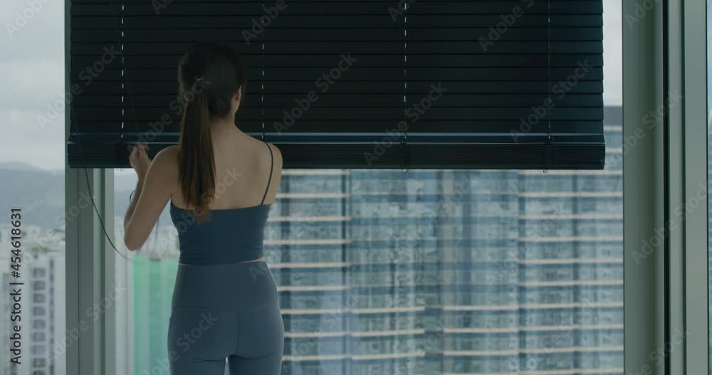 Woman open the window blind at home Woman open the window blind at home