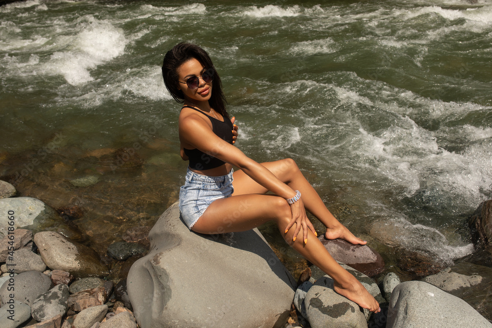 Young black woman tourist relaxes in river.