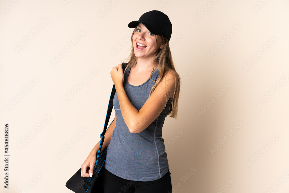 Young sport Lithuanian woman holding a sport bag isolated on beige background celebrating a victory Young sport Lithuanian woman holding a sport bag isolated on beige background celebrating a victory